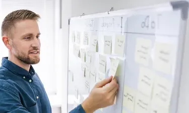 Marketing Student Organizing Tasks with Sticky Notes on Whiteboard